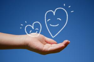 子供の手のひらで微笑むハートの親子